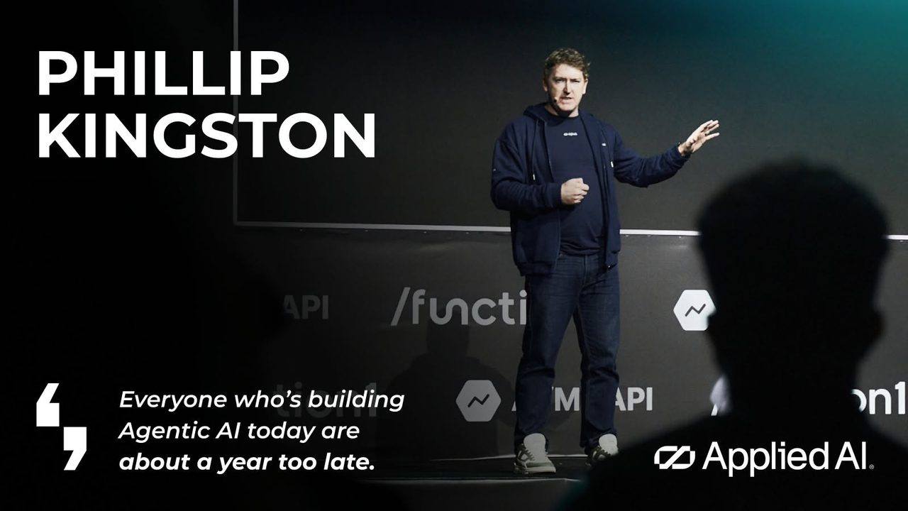 Speaker card for /function1: Phillip Kingston mid-gesture on stage against the conference's logo wall, beside the line “Everyone who's building Agentic AI today are about a year too late” and the AppliedAI mark.