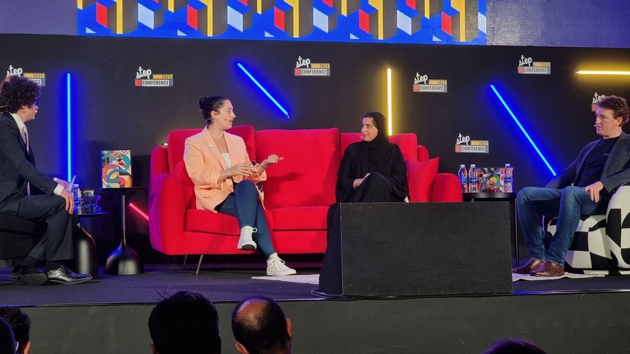 The panel on the Step Conference 2024 stage at Dubai Internet City: a moderator at the left and three panellists across a red sofa and an armchair, under a wall of Step Conference logos and neon strip lights.